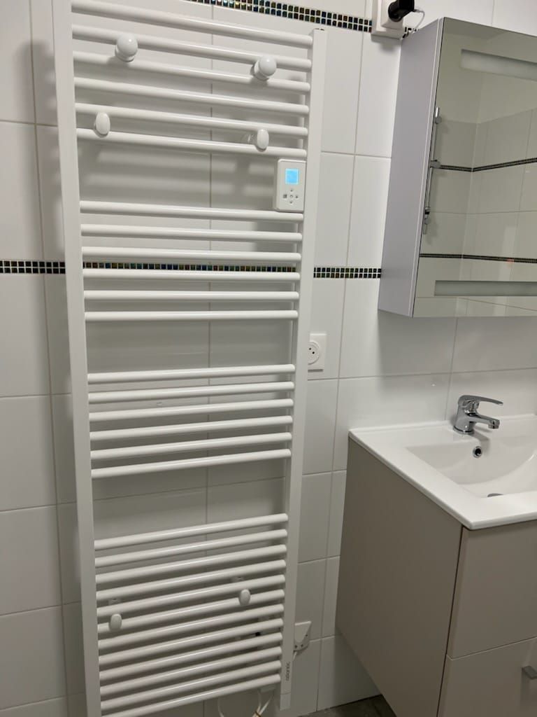Sèche-serviettes installé à côté du meuble avec le lavabo