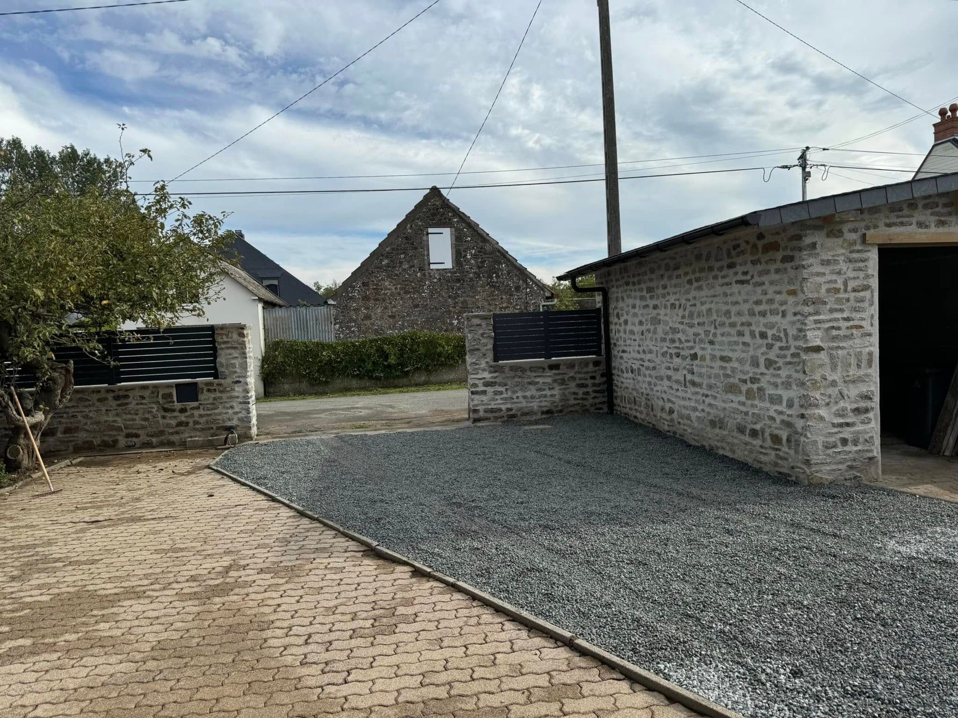 Allée rénovée avec des dalles, à côté du cabanon et des murets reconstruits