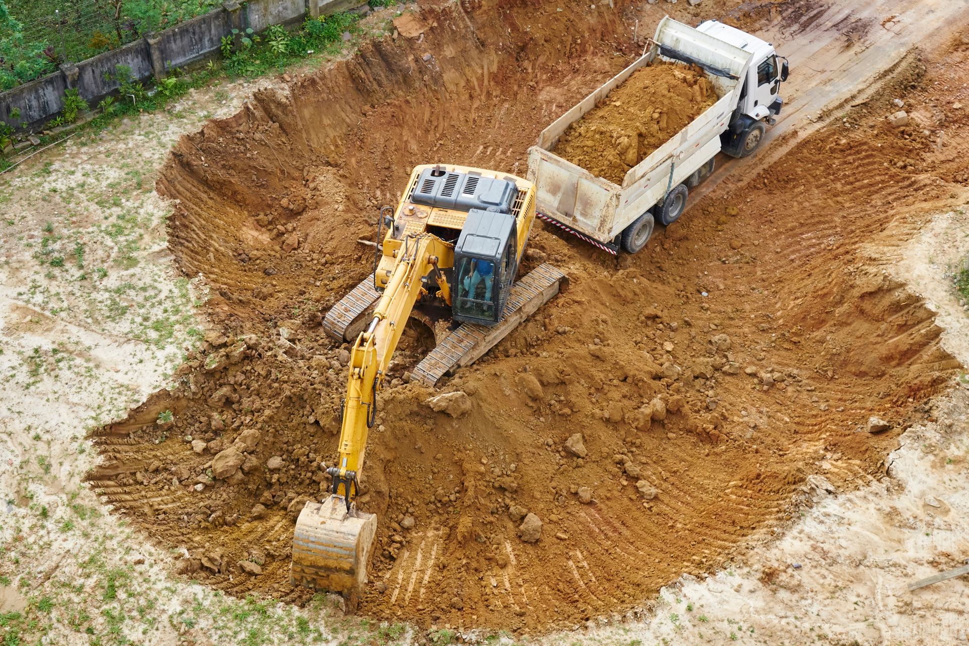 Une excavatrice chargeant de la terre dans un camion à benne basculante sur un chantier de construction.