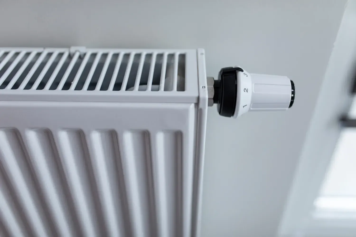Un radiador de panel blanco con una válvula termostática de control de temperatura en blanco.