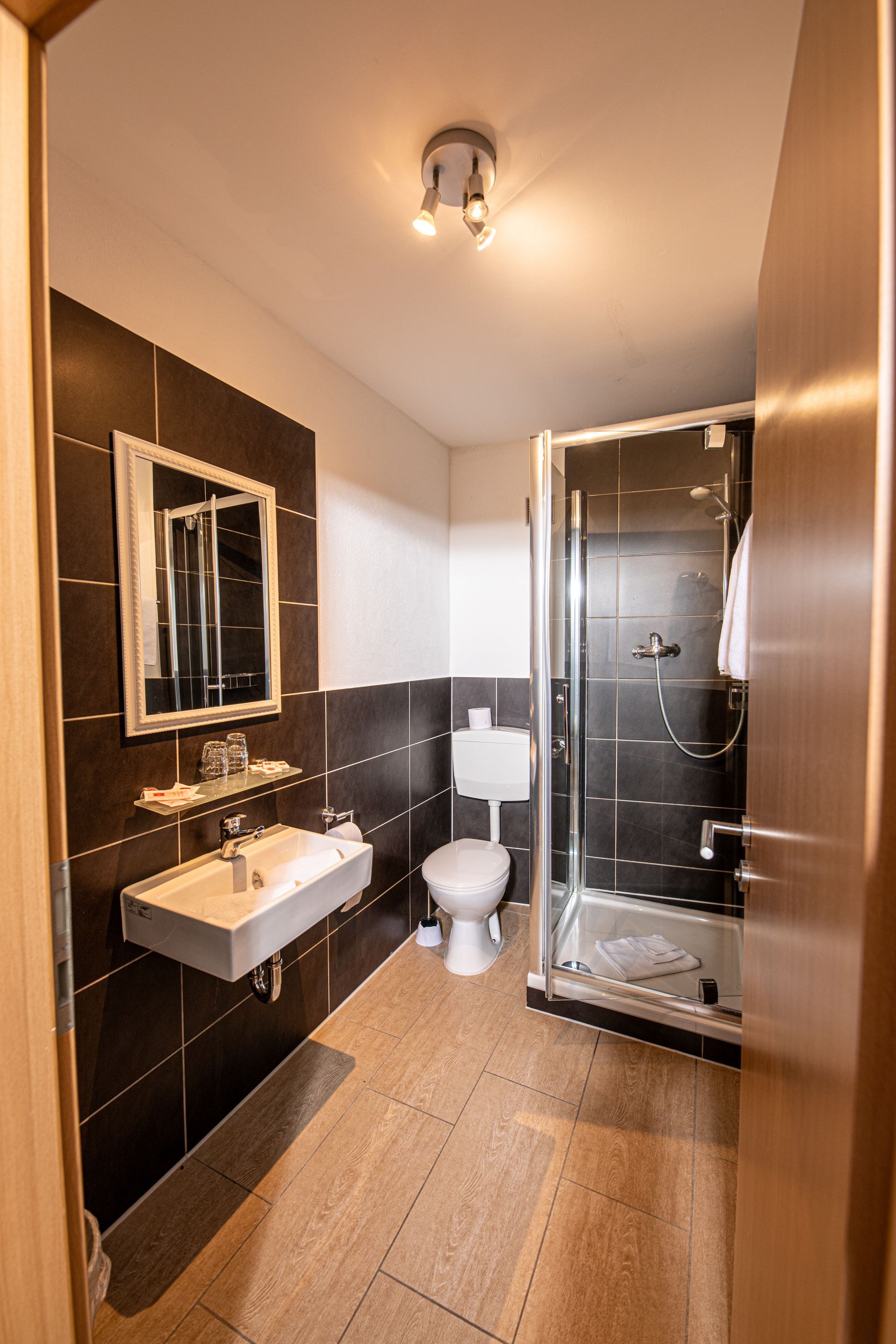 Kleines, modernes Badezimmer mit Dusche, Toilette und Waschbecken im Hotel Gasthof Lamm.
