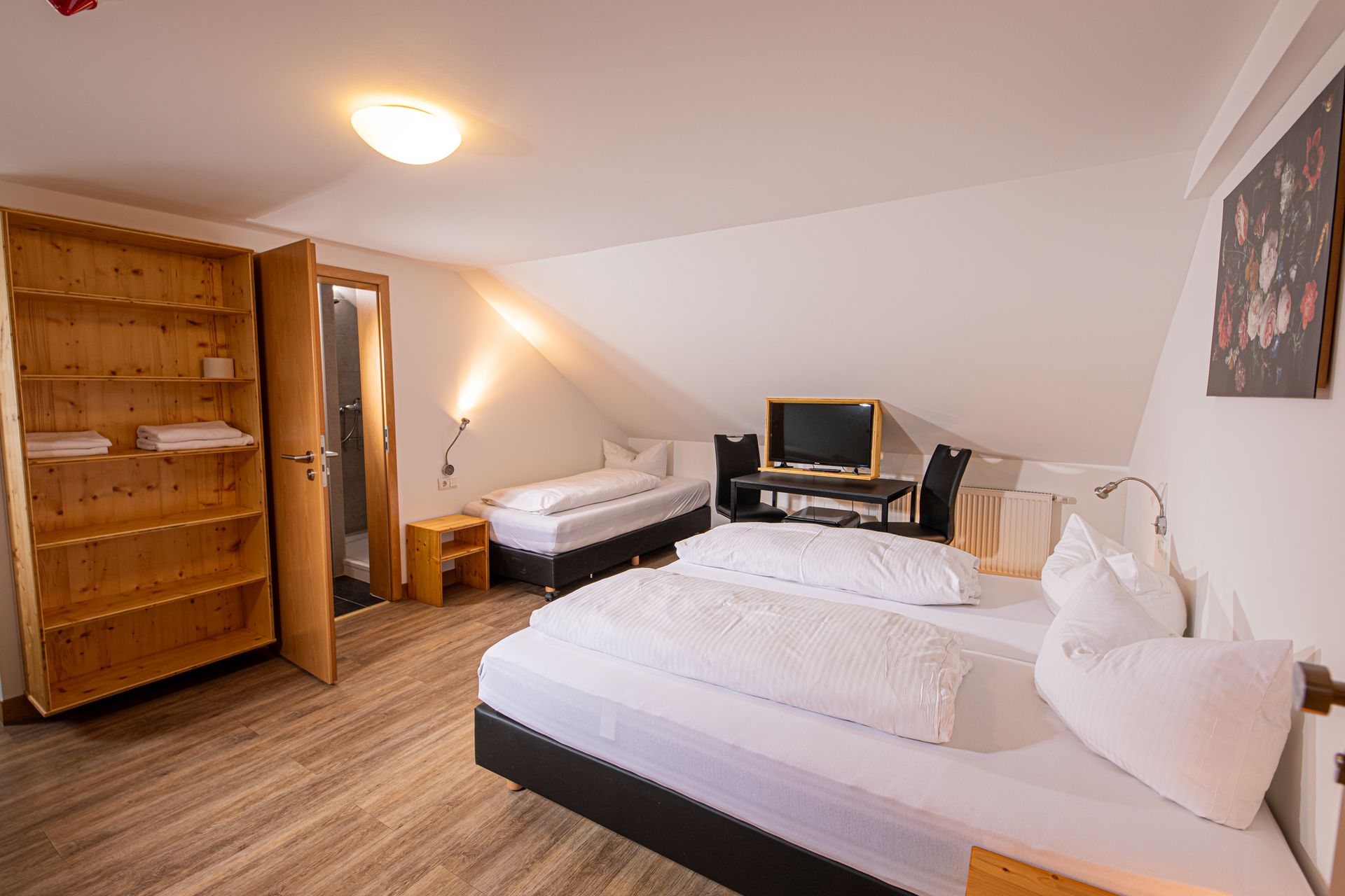 Gemütliches Hotelzimmer mit Dachschräge, drei Betten und TV im Gasthof Lamm