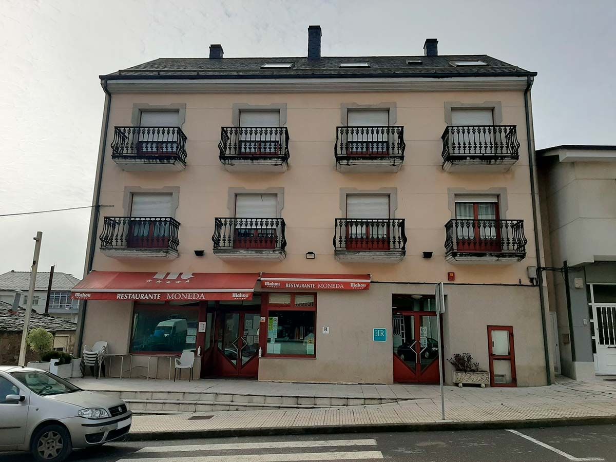 Edificio con restaurante en planta baja, balcones en plantas superiores, cielo nublado.