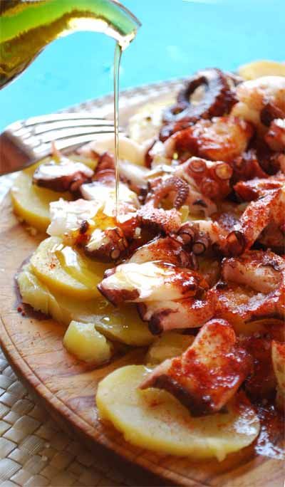 Plato de pulpo: patatas cortadas en rodajas sobre las que se coloca pulpo, pimentón y se vierte aceite de oliva por encima.