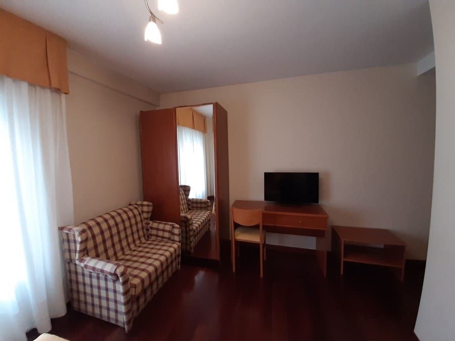 Una habitación de hotel con un sofá a cuadros, muebles de madera y un espejo.