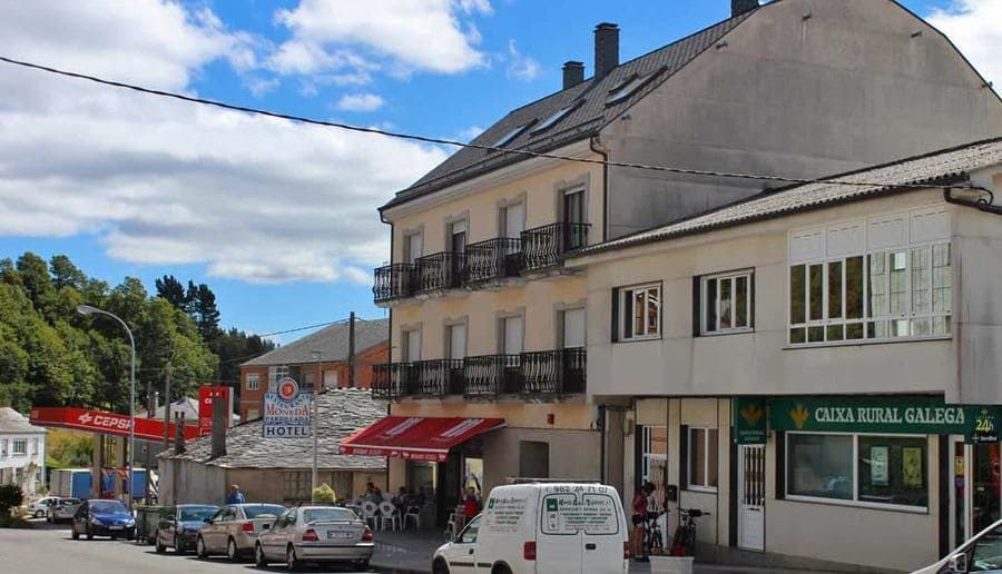 Edificios y coches aparcados se alinean en una calle bajo un cielo parcialmente nublado.
