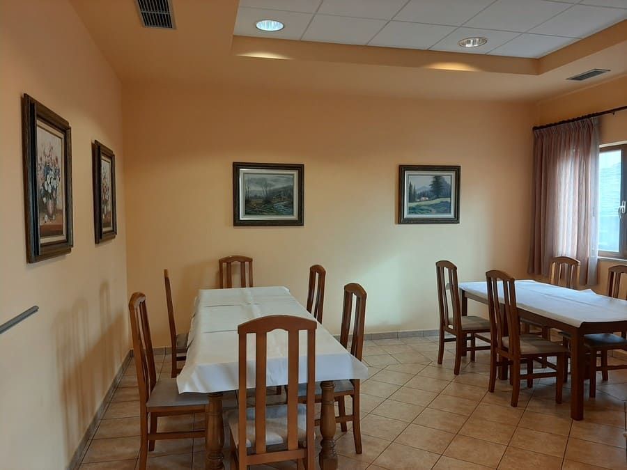 Comedor con varias mesas de madera dispuestas con manteles blancos, sillas y obras de arte enmarcadas en las paredes.