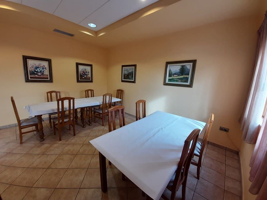 Comedor de restaurante con mesas preparadas para los invitados, arte enmarcado en paredes de color canela, piso de baldosas e iluminación suave.