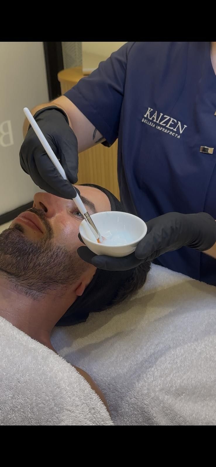 Mujer recibiendo un tratamiento facial con un dispositivo portátil en un entorno de spa.