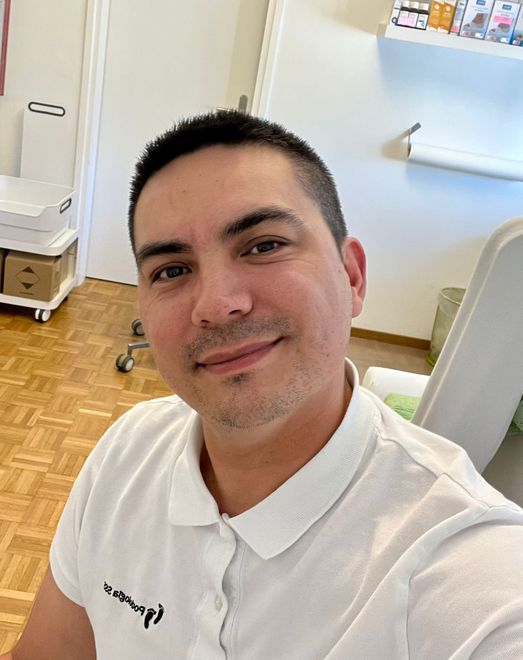 Una persona si scatta un selfie in una stanza luminosa, indossando una polo bianca e sorridendo.