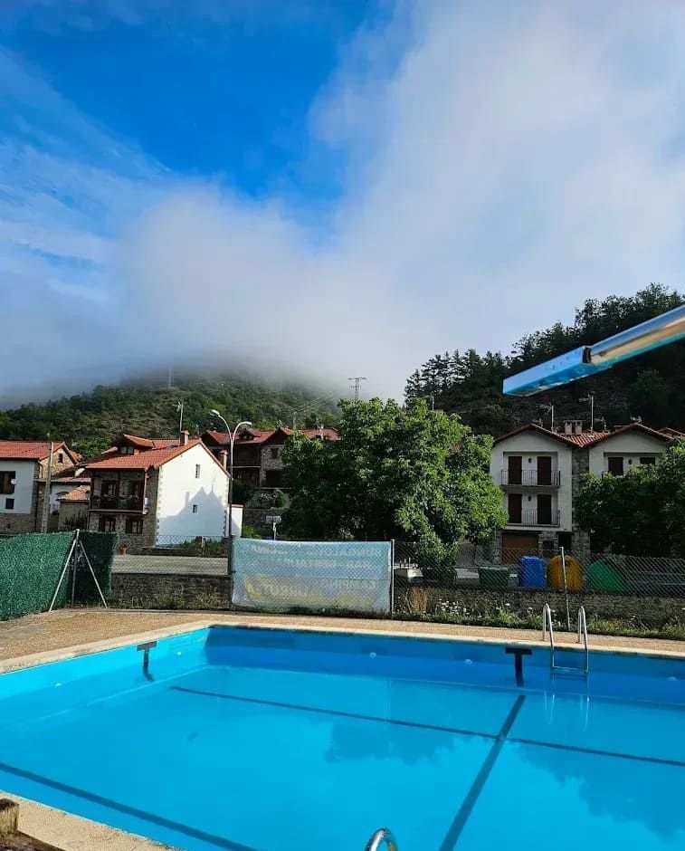 Una gran piscina rodeada de casas y árboles con un cielo nublado al fondo.