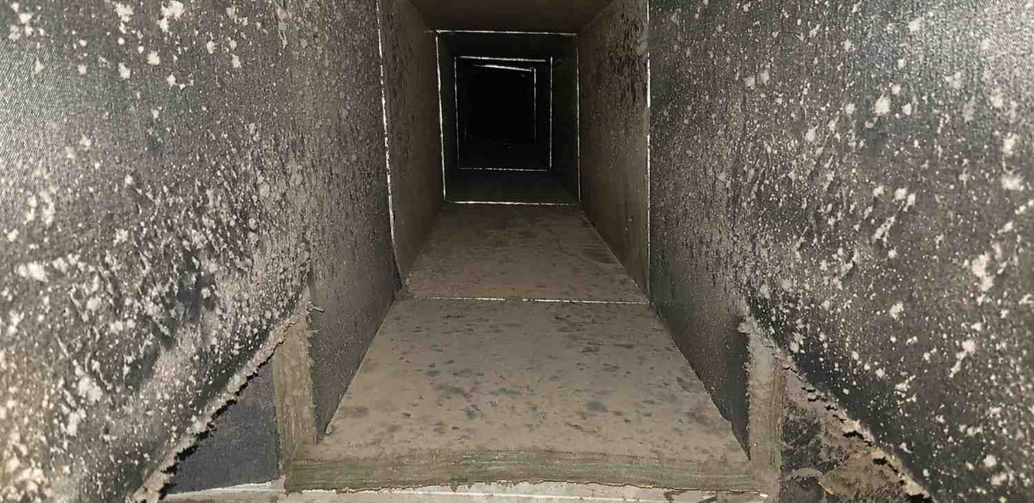 Estrecho túnel de hormigón con paredes grises rugosas y una abertura oscura al final.