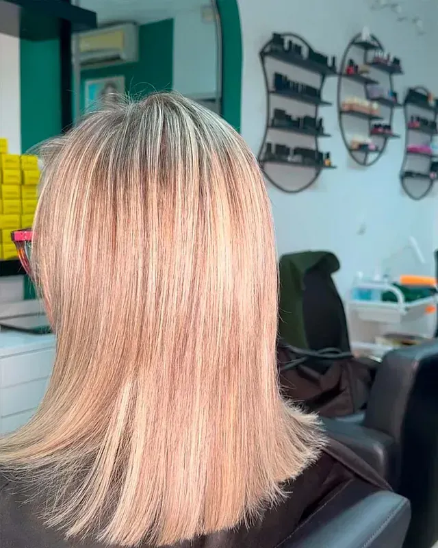 Una mujer con cabello rubio está sentada en una silla en un salón.