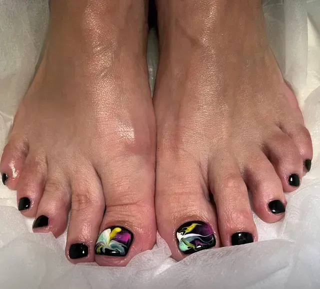 Un primer plano de los pies de una mujer con uñas de colores.