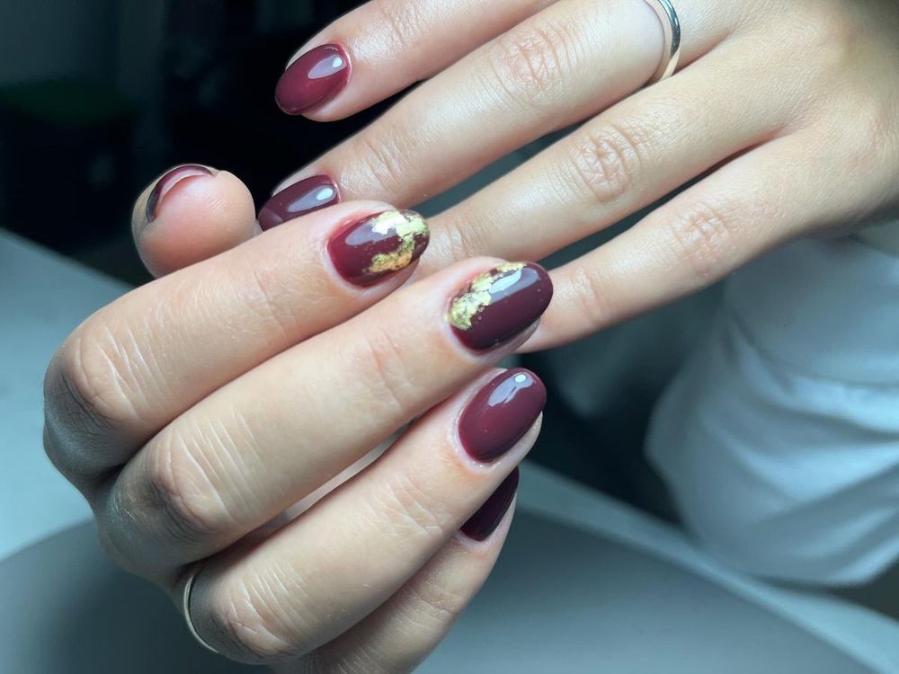 Un primer plano de las uñas de una mujer con un anillo en el dedo.