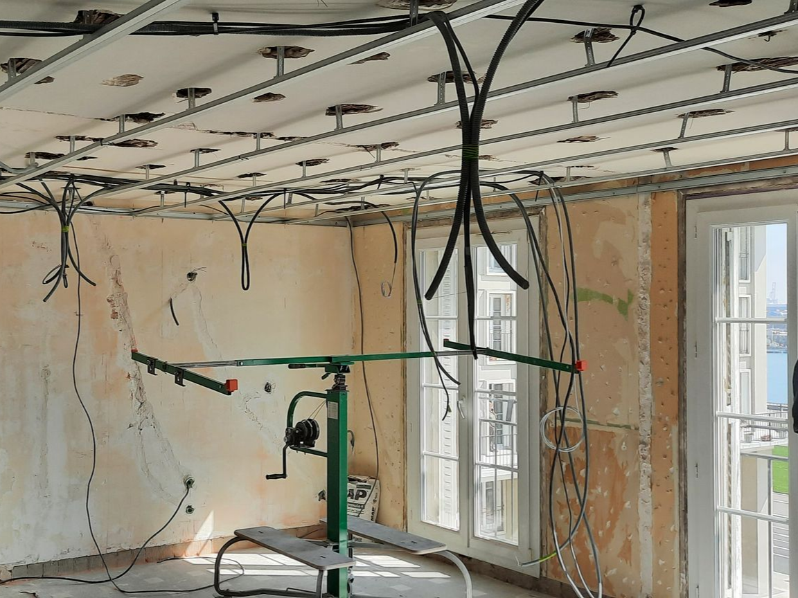 Câbles sortant du plafond dans une pièce en rénovation
