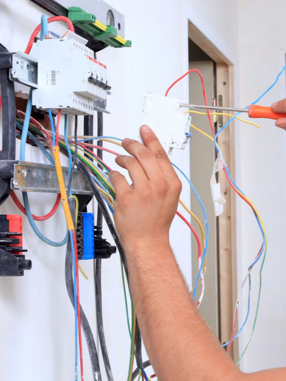 Personne en train de fixer les éléments d'un tableau électrique