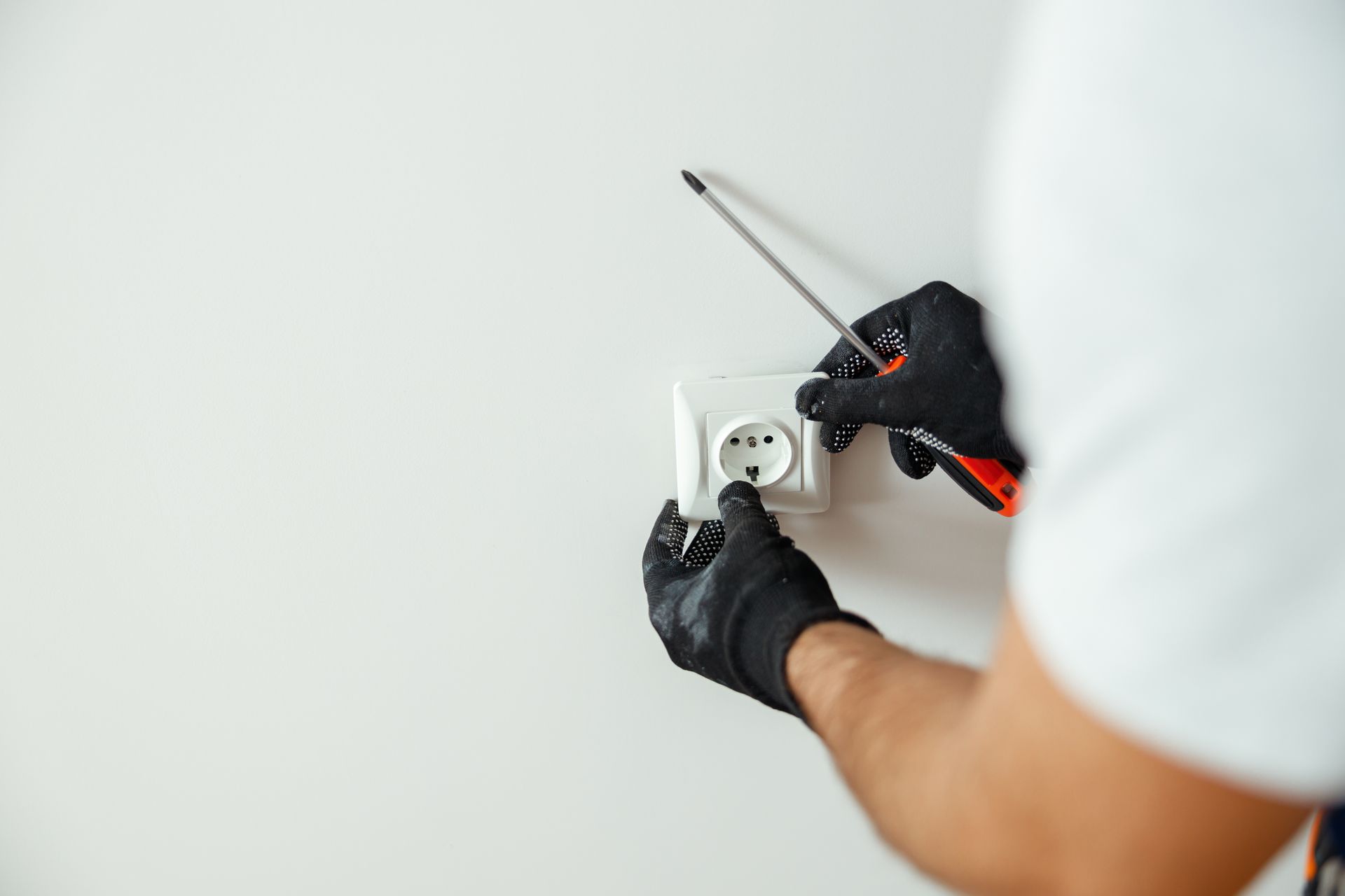 Personne remettant le cache d'une prise blanc sur un mur blanc 