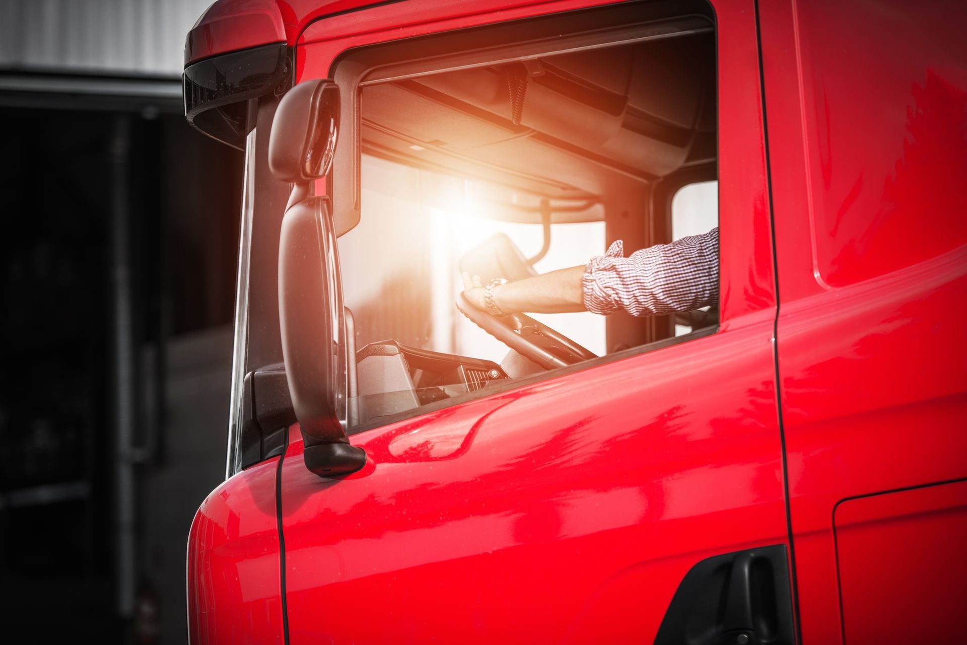 Κόκκινο εσωτερικό καμπίνας φορτηγού, ηλιακό φως που λάμπει μέσα από το παράθυρο, ορατά τα πόδια του οδηγού.