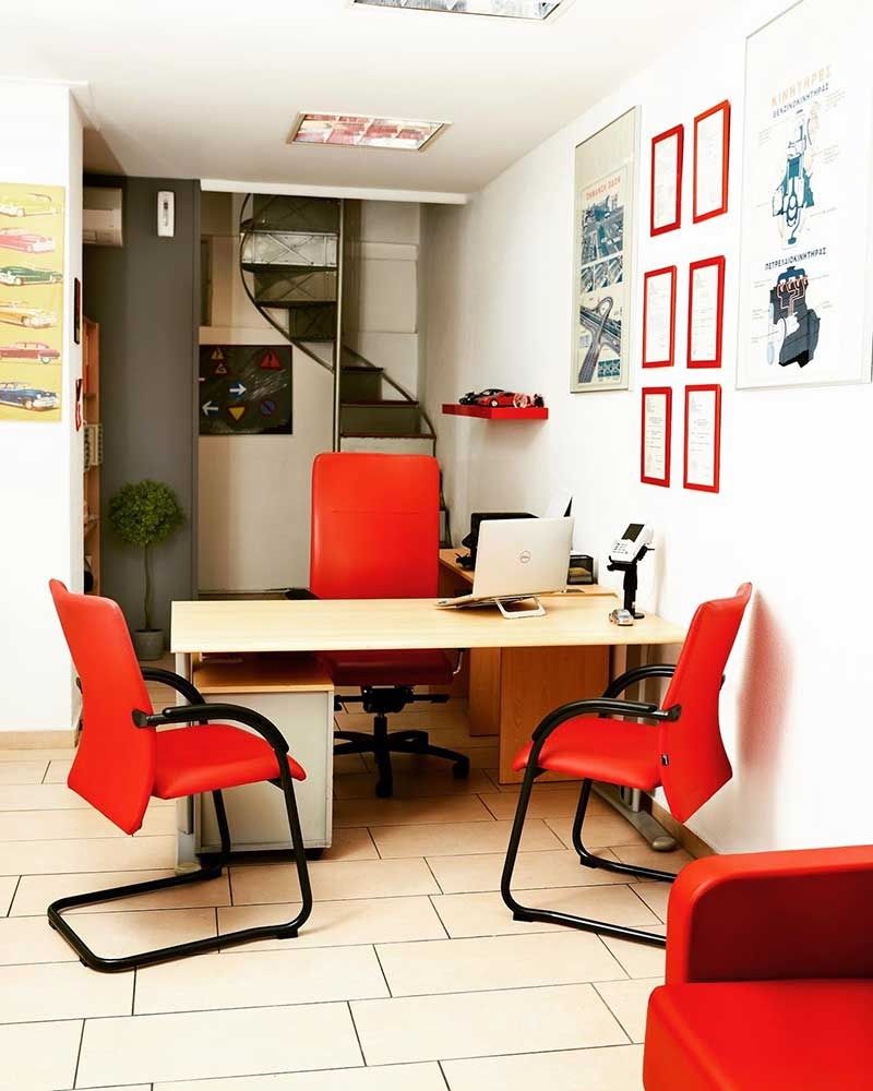 Εσωτερικό γραφείου με κόκκινες καρέκλες, ένα γραφείο με φορητό υπολογιστή και μια σπειροειδή σκάλα που οδηγεί στον επάνω όροφο.