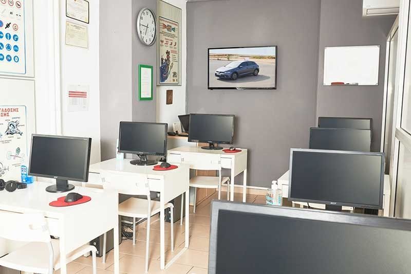 Ένα εργαστήριο υπολογιστών με αρκετούς επιτραπέζιους υπολογιστές και γραφεία, μια τηλεόραση που απεικονίζει ένα αυτοκίνητο και εκπαιδευτικές αφίσες.
