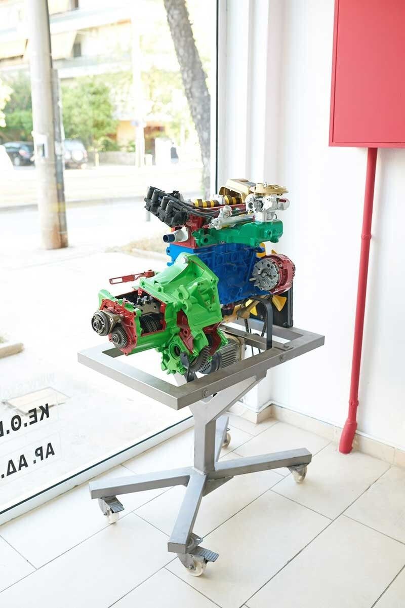 Μοντέλο μηχανής Lego σε τροχήλατη βάση, που εκτίθεται κοντά σε παράθυρο και κόκκινο στύλο.