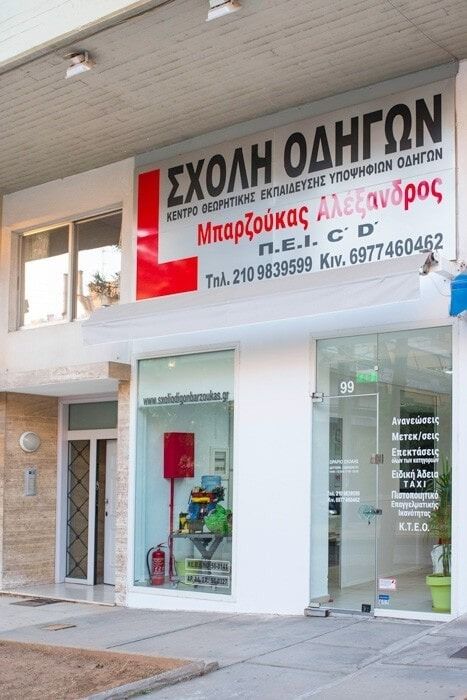 Driving school storefront with signage in Greek.