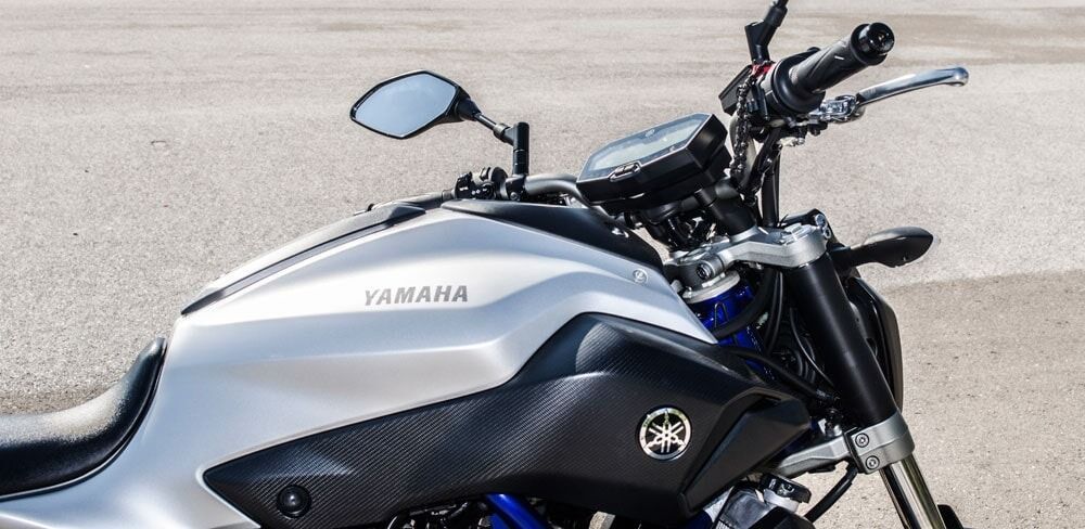 Ασημένια μοτοσικλέτα Yamaha MT-07 σε γκρι επιφάνεια. Η μοτοσικλέτα έχει μαύρες λεπτομέρειες και ένα λογότυπο Yamaha στο ρεζερβουάρ καυσίμου.