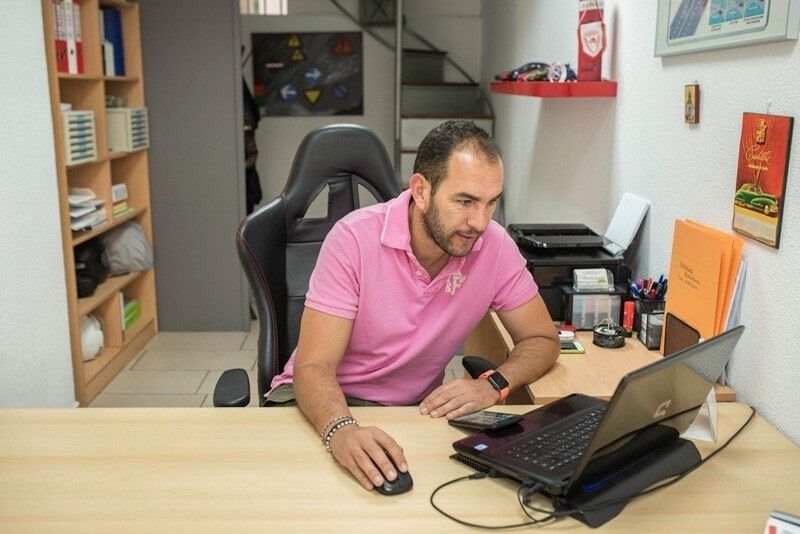 Άνδρας με ροζ πουκάμισο εργάζεται σε φορητό υπολογιστή στο γραφείο.