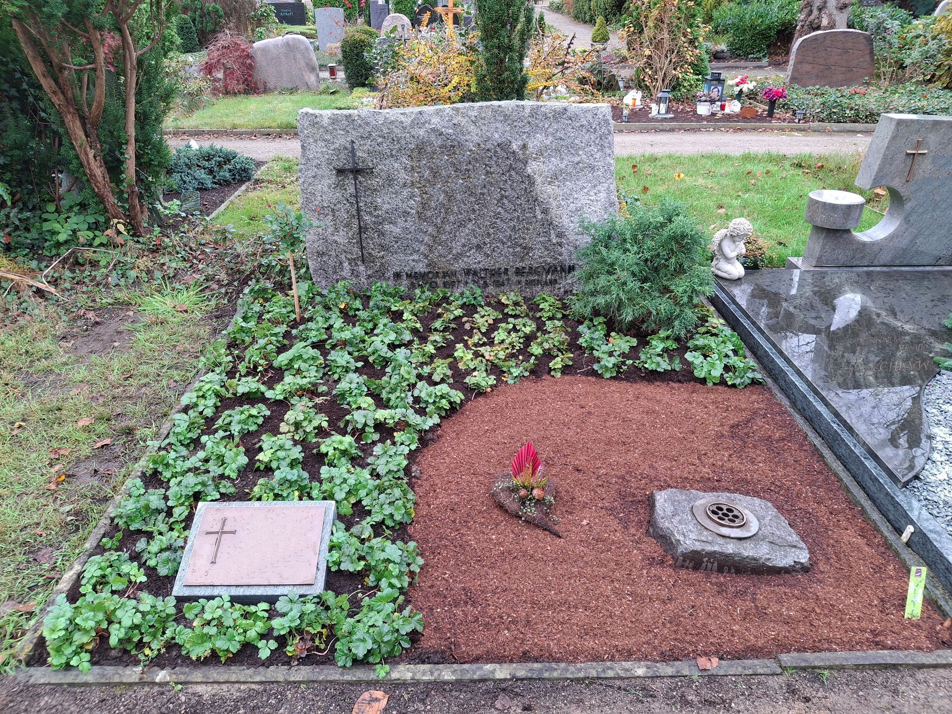 Ein Grab auf einem Friedhof mit Blumen und Grabsteinen.