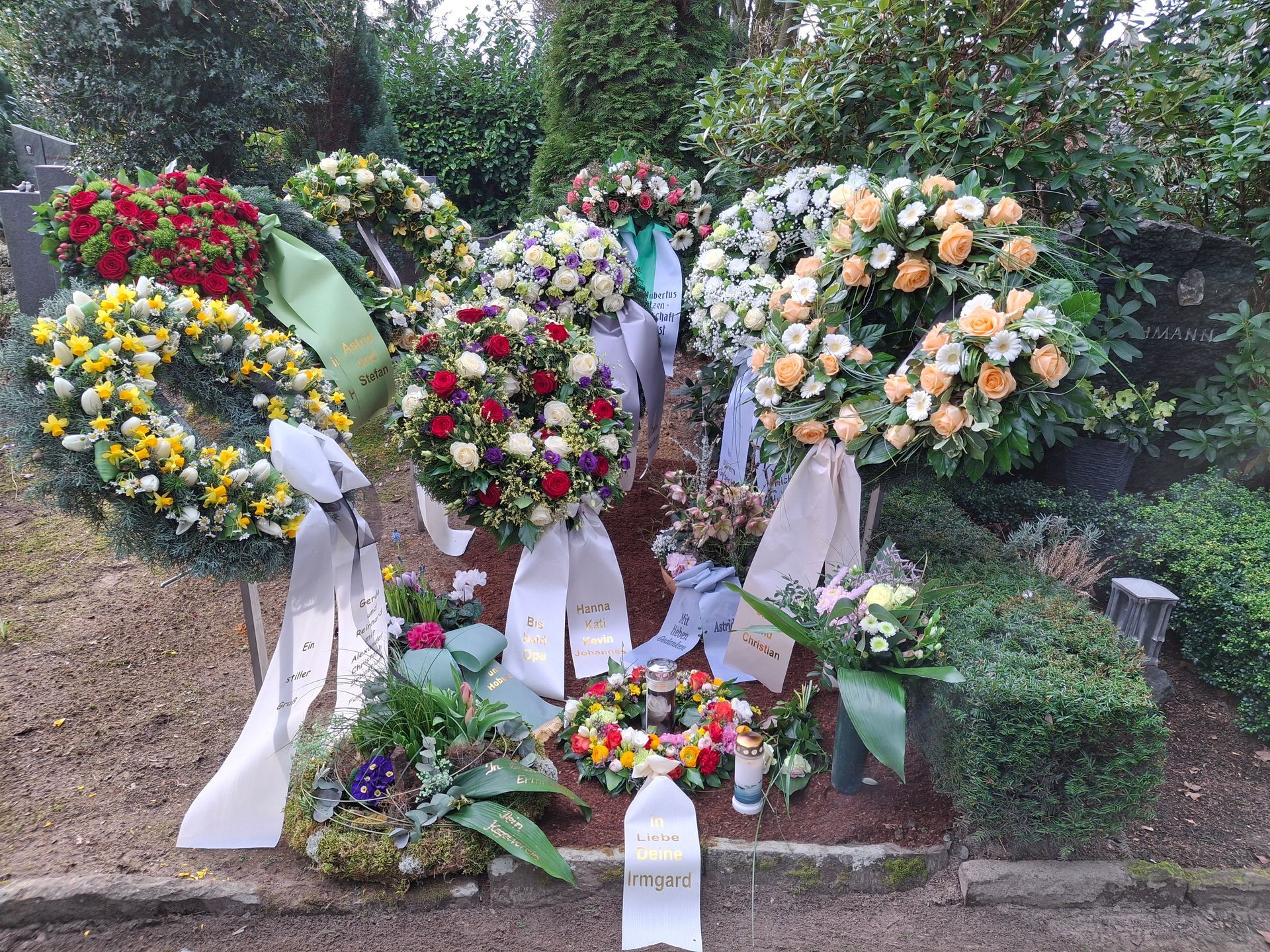 Auf einem Grab liegt ein Bündel Kränze.