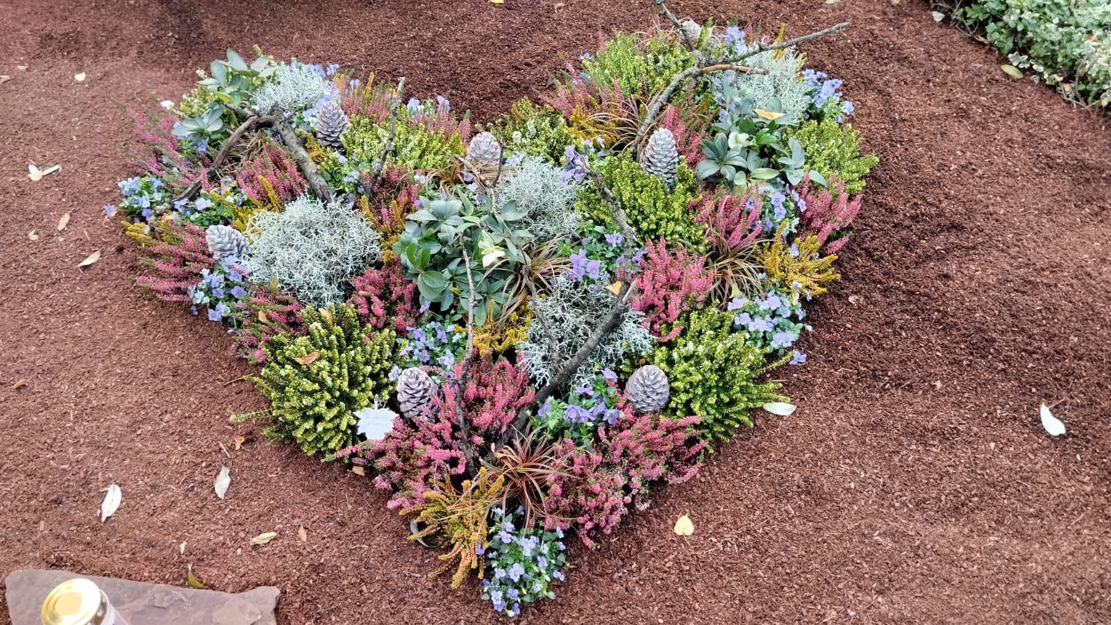 Auf einem Grab liegt ein Herz aus Blumen.