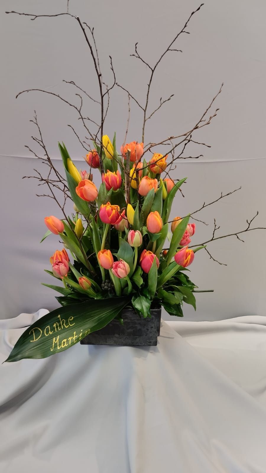 Auf einem Tisch steht eine Vase voller Blumen und Zweige.