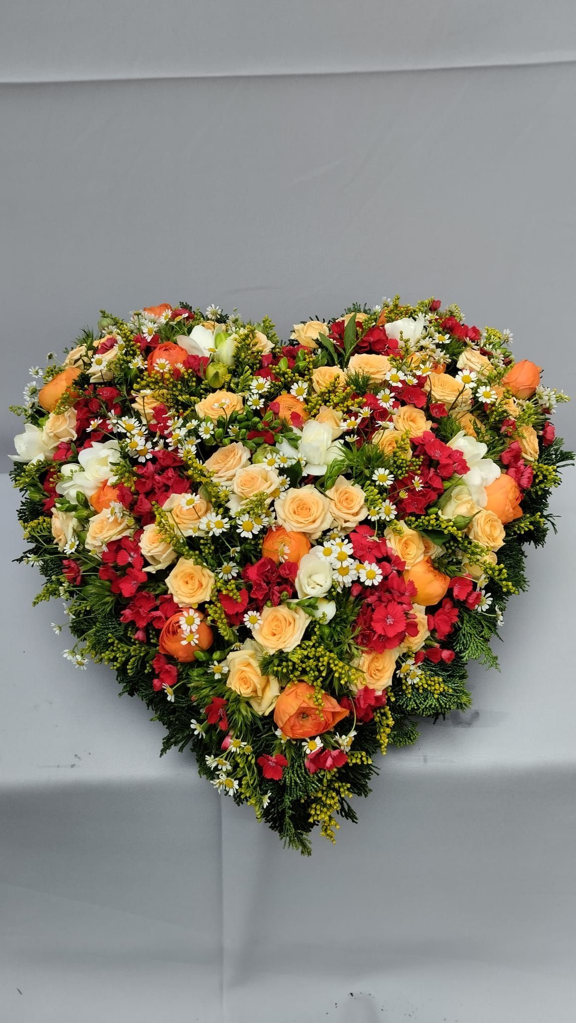 Auf einem Tisch steht ein herzförmiger Blumenkranz.