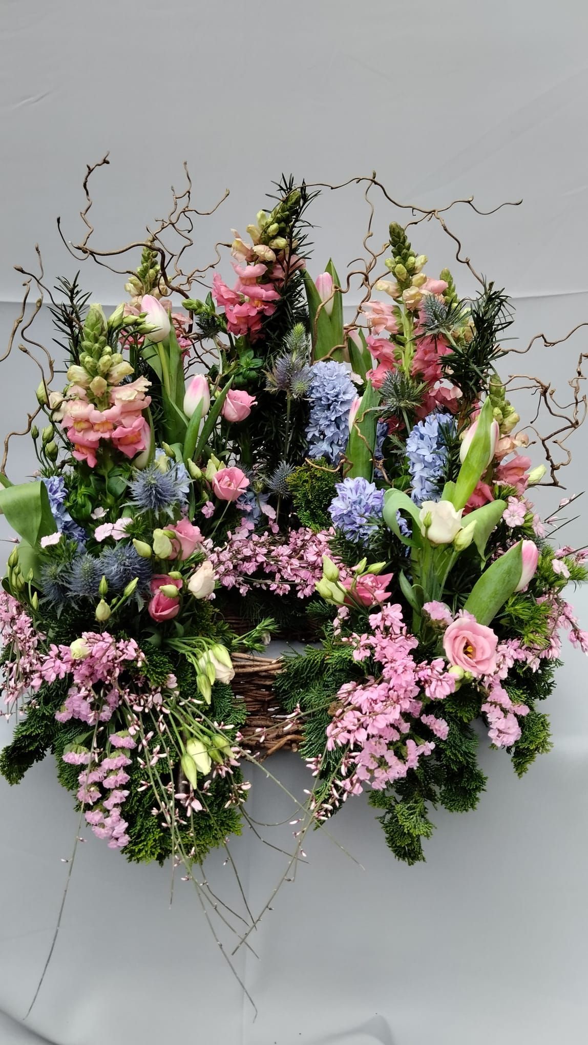 Auf einem Tisch steht ein Korb voller rosa und blauer Blumen.