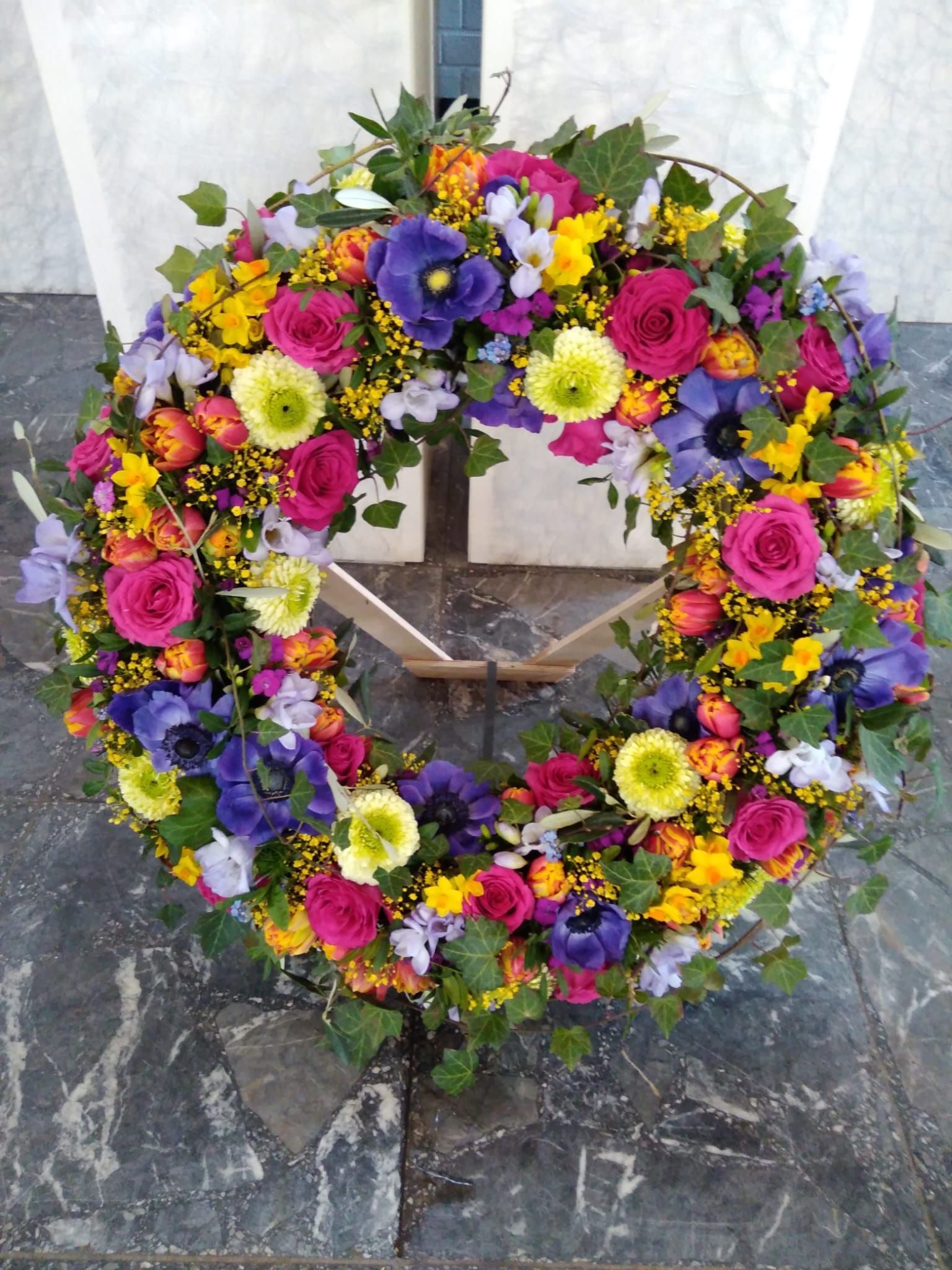 Auf einem Steinboden liegt ein bunter Blumenkranz.