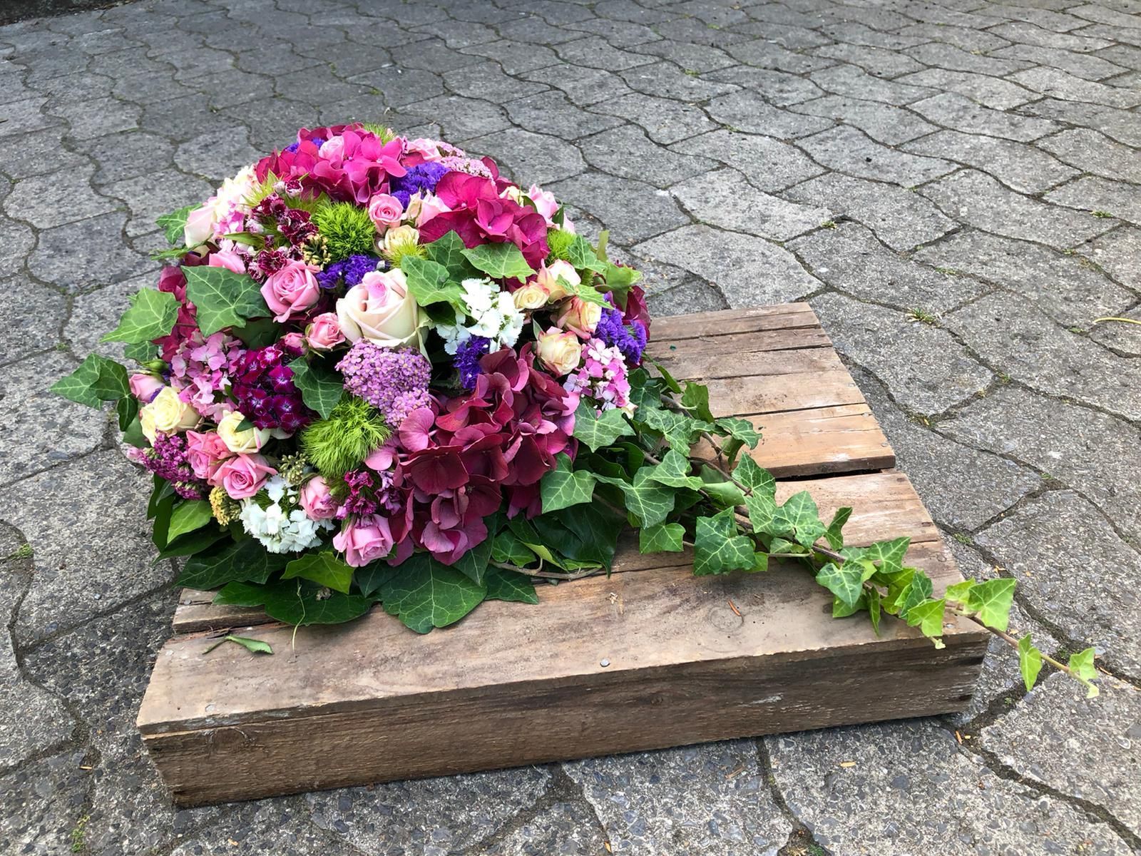 Auf einer Holzkiste steht ein Blumenstrauß.