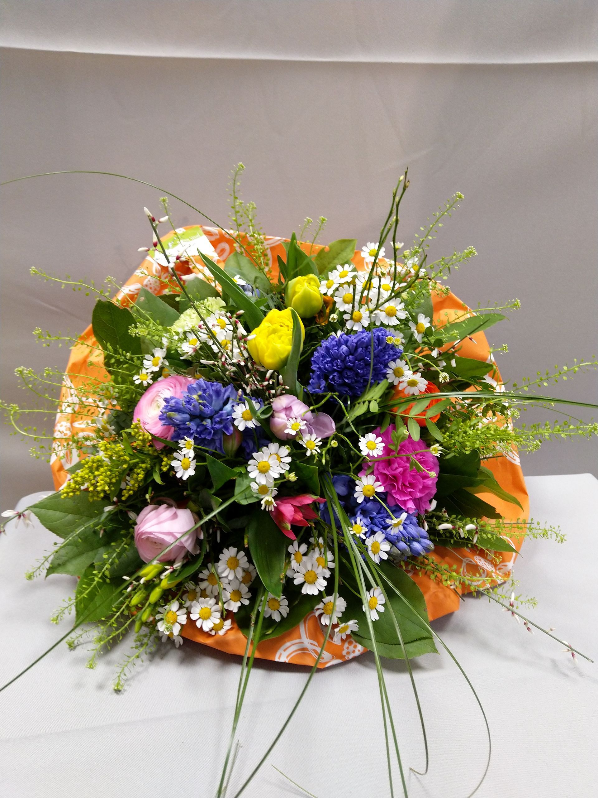 Ein Blumenstrauß ist in orangefarbenes Papier eingewickelt