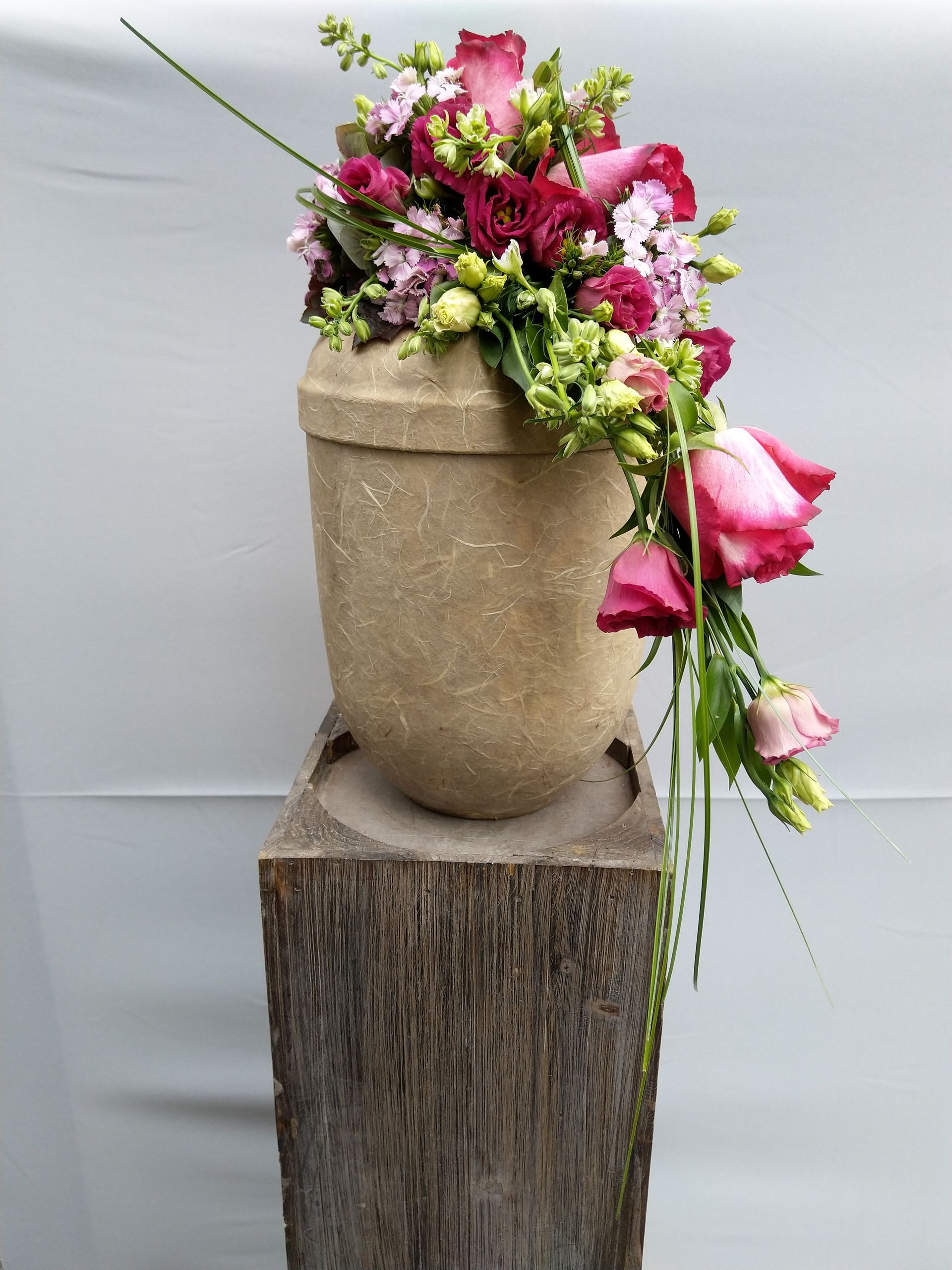 Eine mit Blumen gefüllte Vase steht auf einem Holzblock