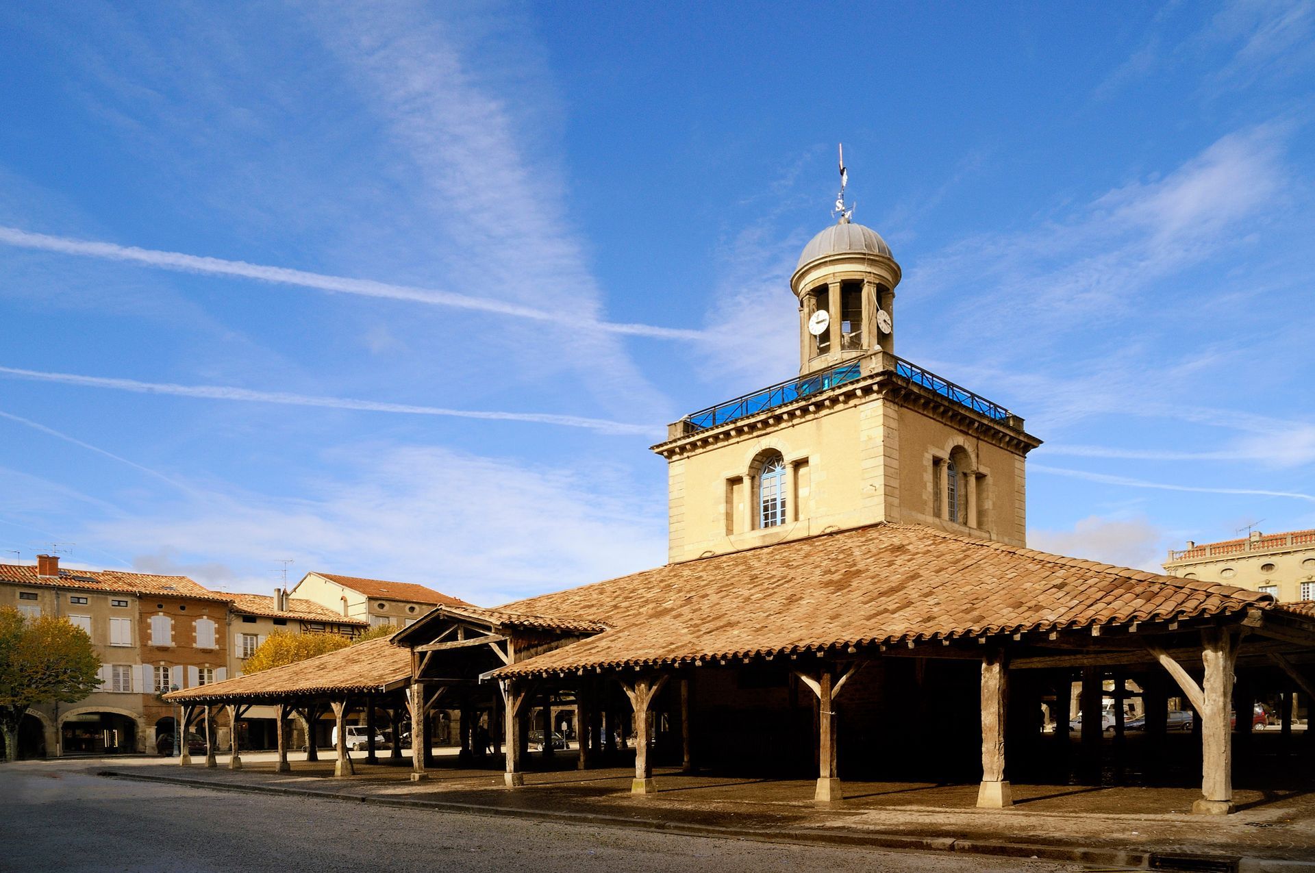 Un bâtiment de la place du marché, avec un toit de tuiles et une tour d'horloge, sous un ciel bleu.