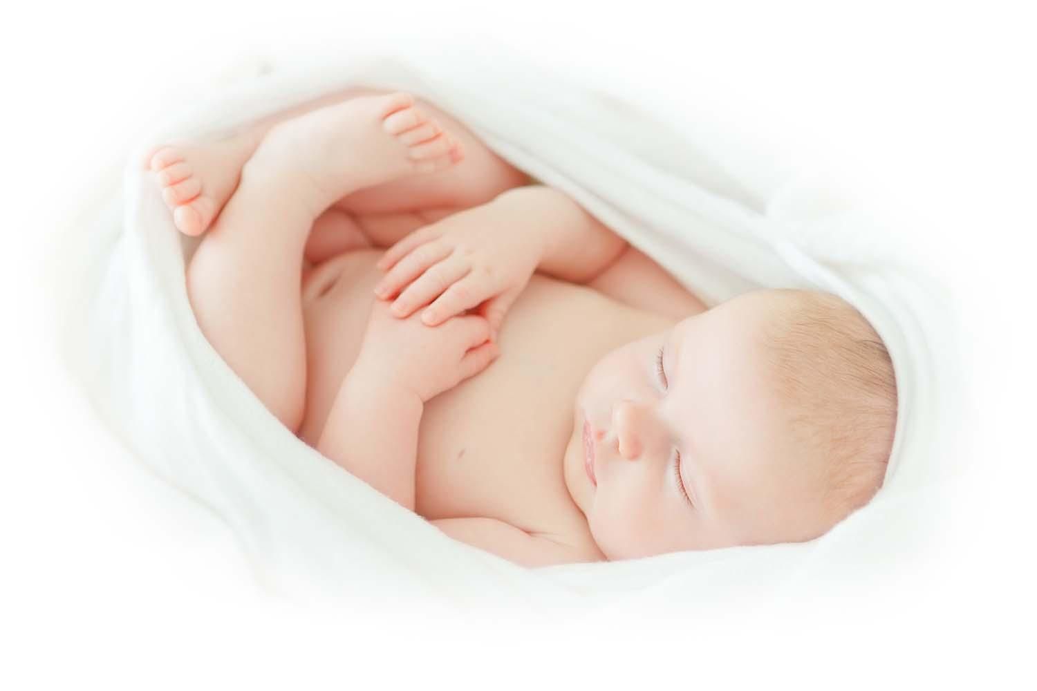 Bébé endormi, enveloppé dans une couverture blanche, recroquevillé sur un fond blanc doux