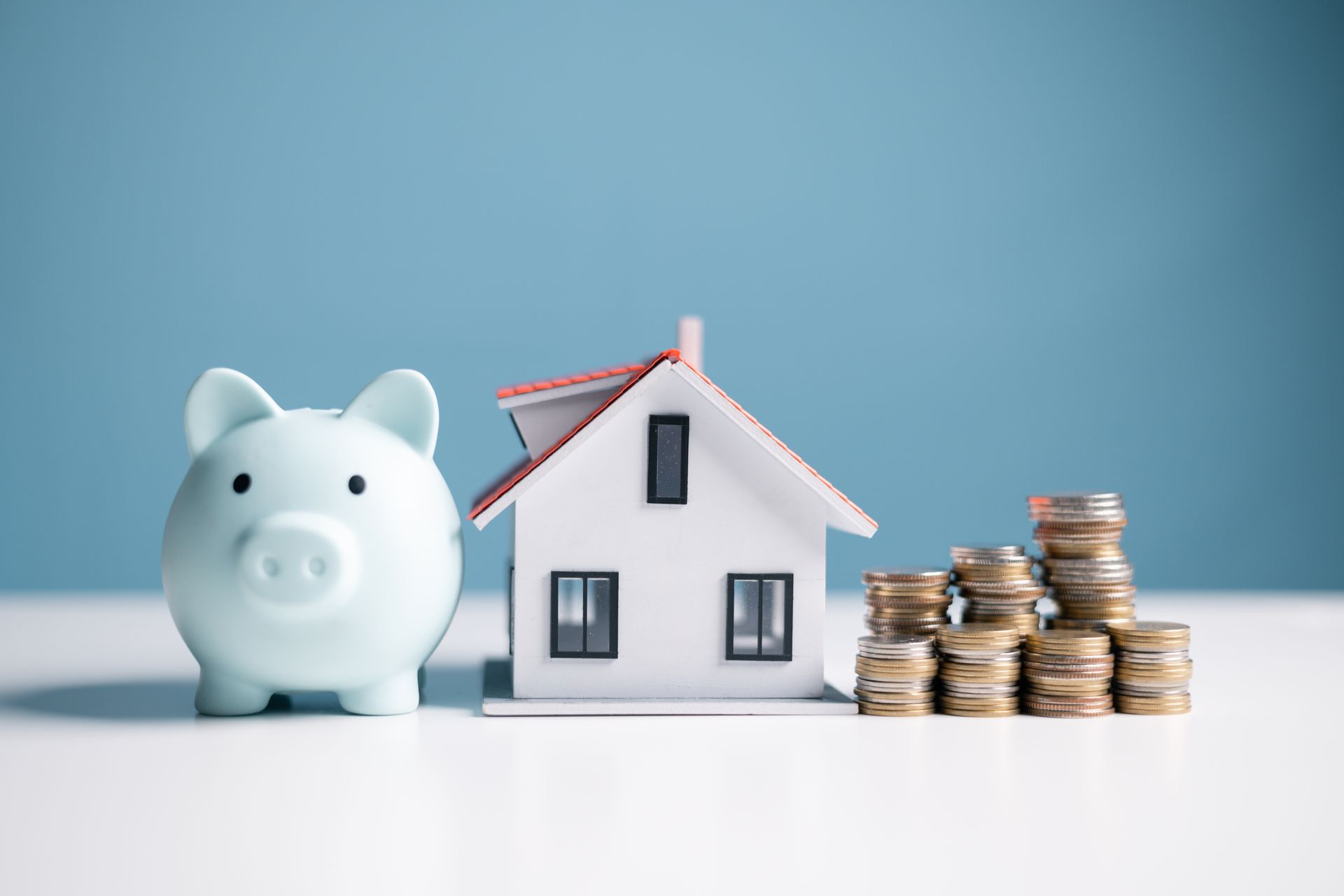 Une tirelire avec une maison et des pièces de monnaie