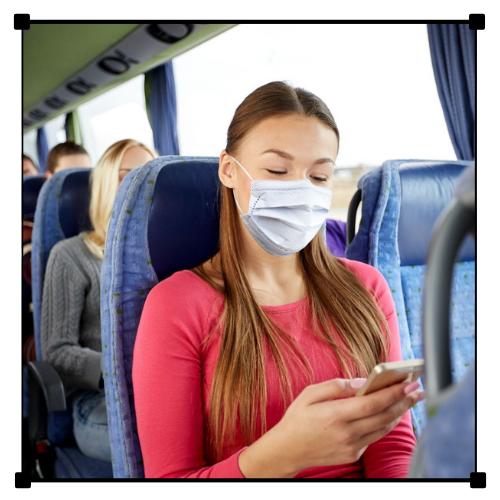 Una mujer que lleva una mascarilla mira su teléfono en un autobús.
