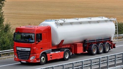 Un camión semirremolque rojo y blanco circula por una autopista.