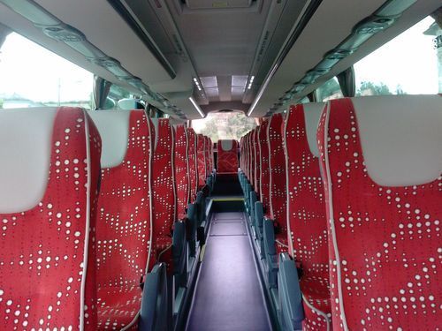 El interior de un autobús con asientos rojos y blancos.