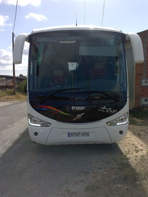 Un autobús blanco está estacionado al costado de la carretera.