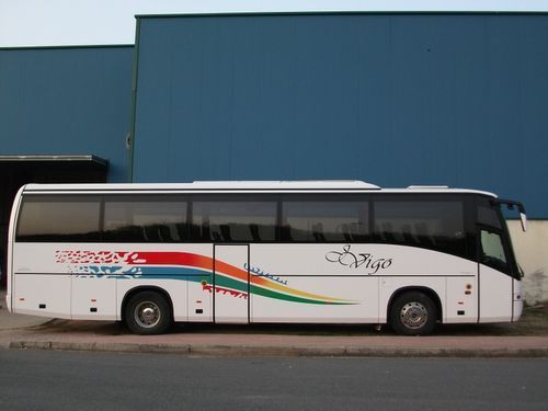 Un autobús blanco con la palabra Vigo en el lateral está aparcado delante de un edificio azul.