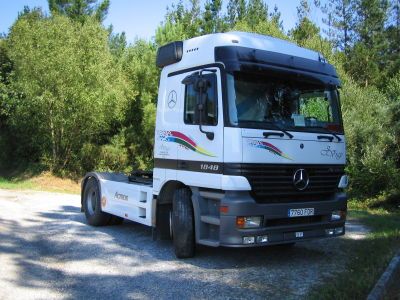 Una camioneta Mercedes blanca está estacionada en un camino de grava.