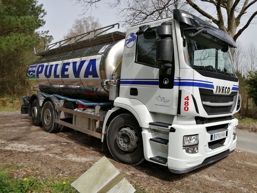 Un camión cisterna blanco y azul está estacionado al costado de la carretera.