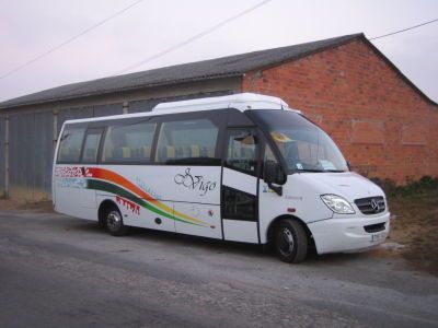 Un autobús blanco está estacionado frente a un edificio de ladrillo.